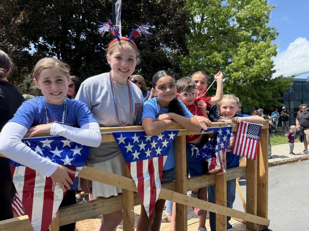 students ride on patriotic parade float