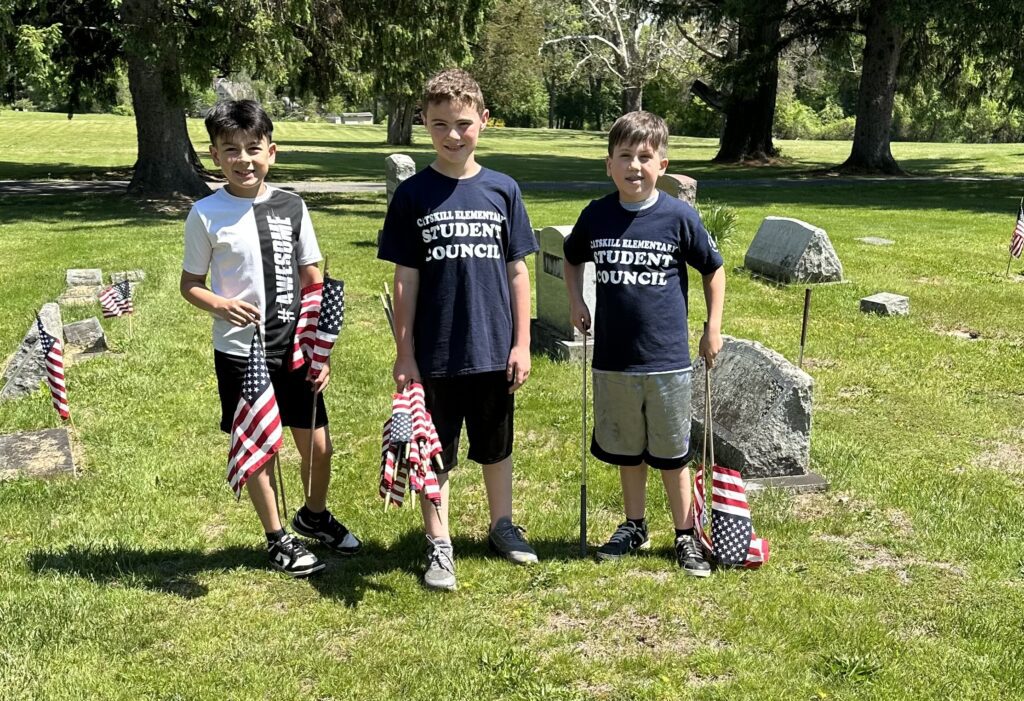 three boys with small flags in cemetery