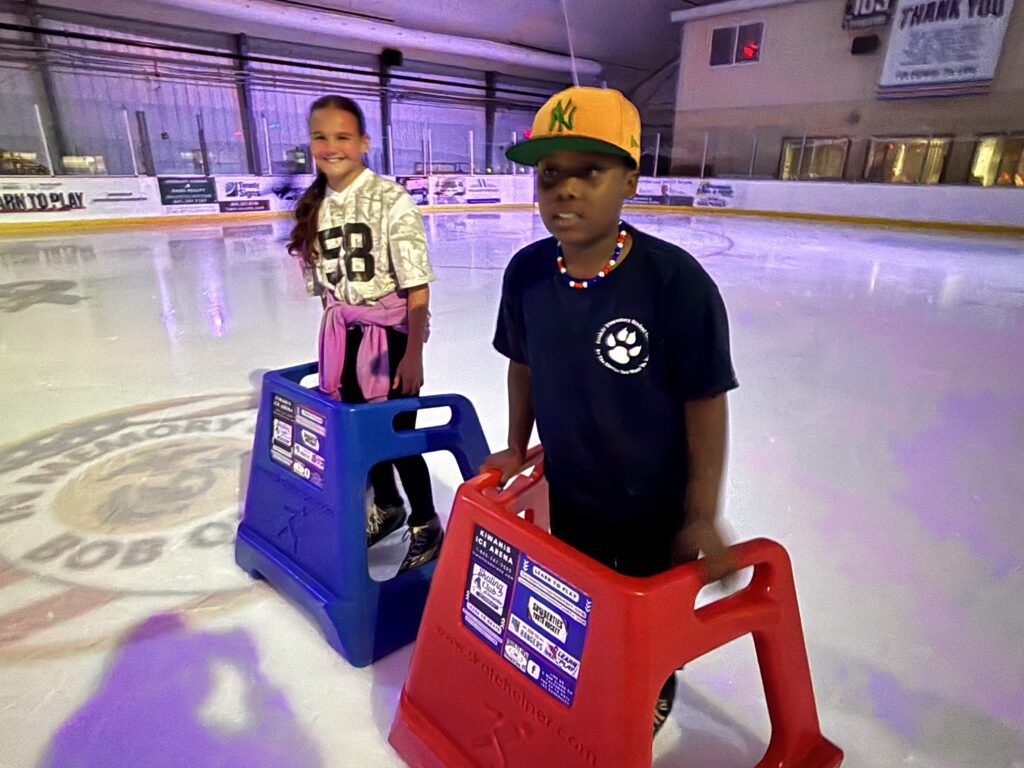 students skating on ice using skate helpers