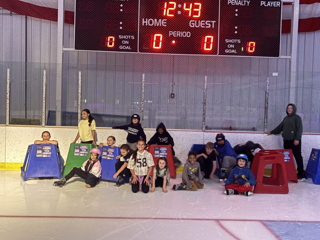 students and parents pose for group photo on ice rink