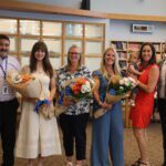 thre women holding flowers pose with school adminstrators