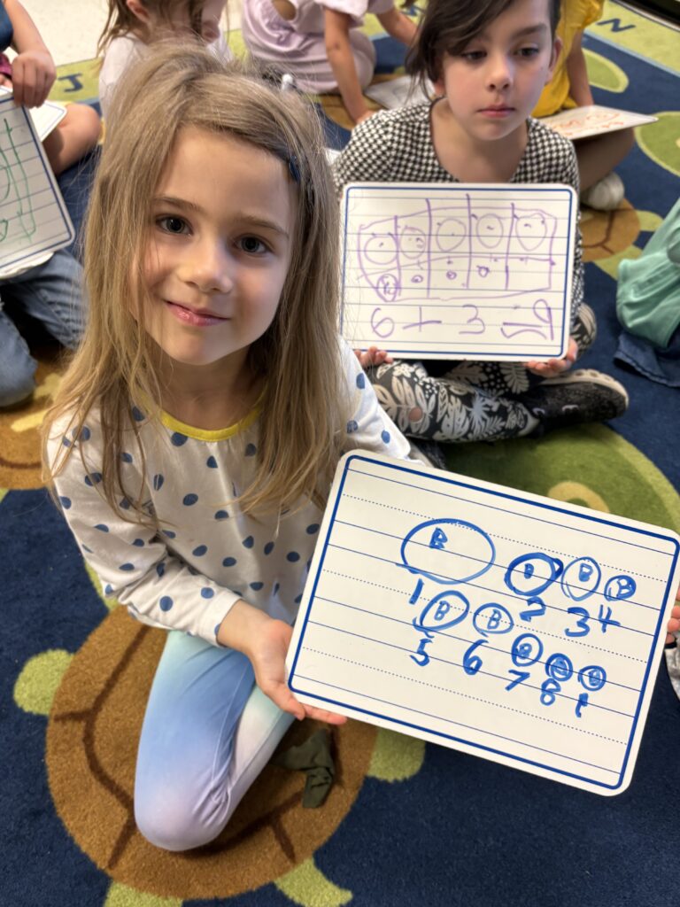 girl holding math board with math problem written out on it