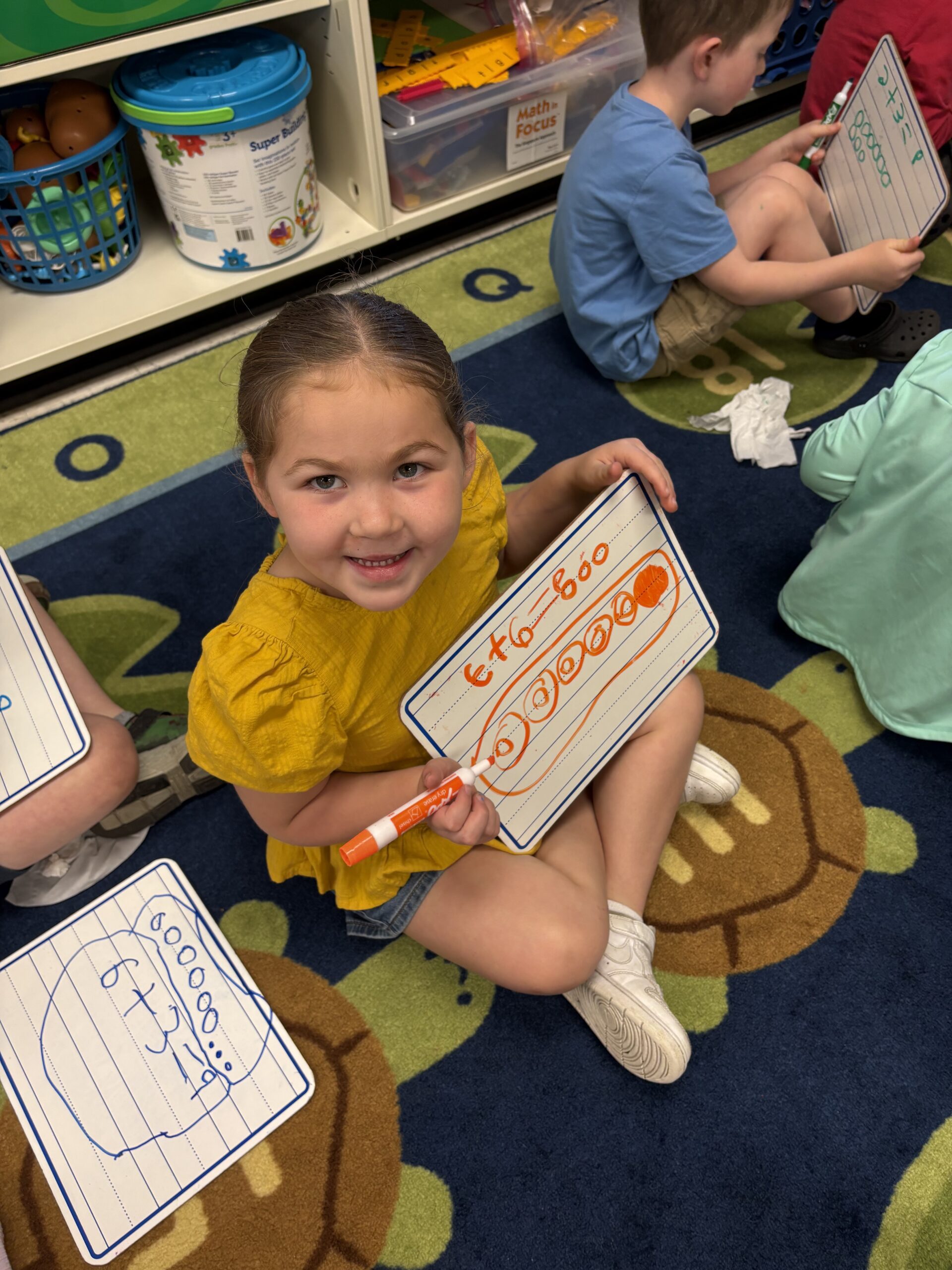 girl holding math board with math problem written out on it