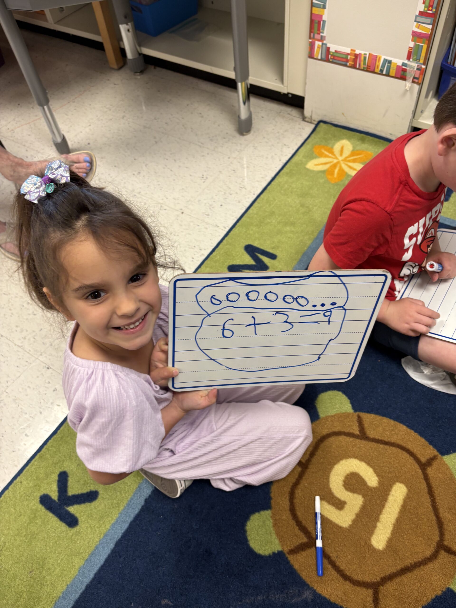 girl holding math board with math problem written out on it