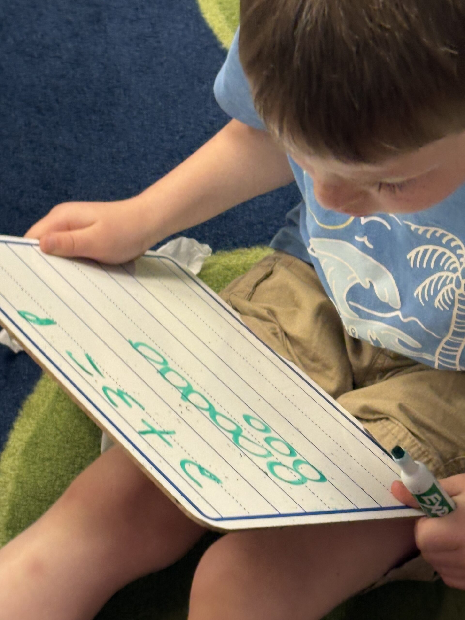 Boy solving math problem on dry erase board