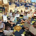 student seated on rug holding math boards