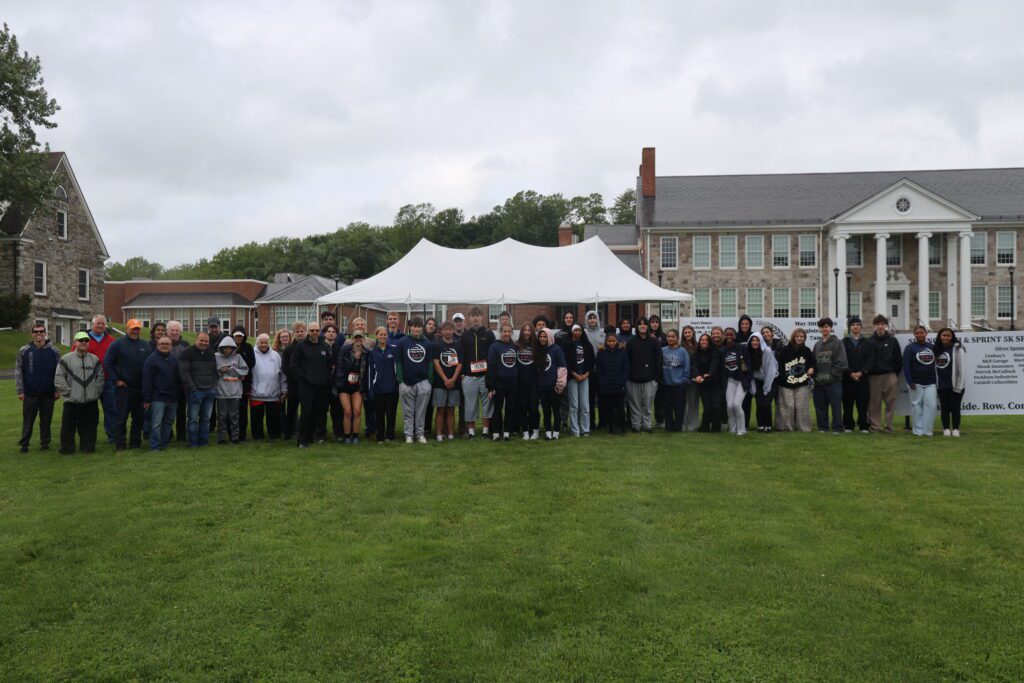 large group of people posing for photo under tent in front of Catskill Middle School