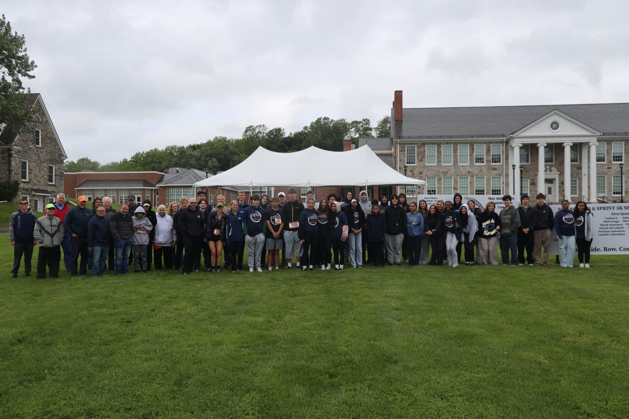 large group of people posing for photo under tent in front of Catskill Middle School